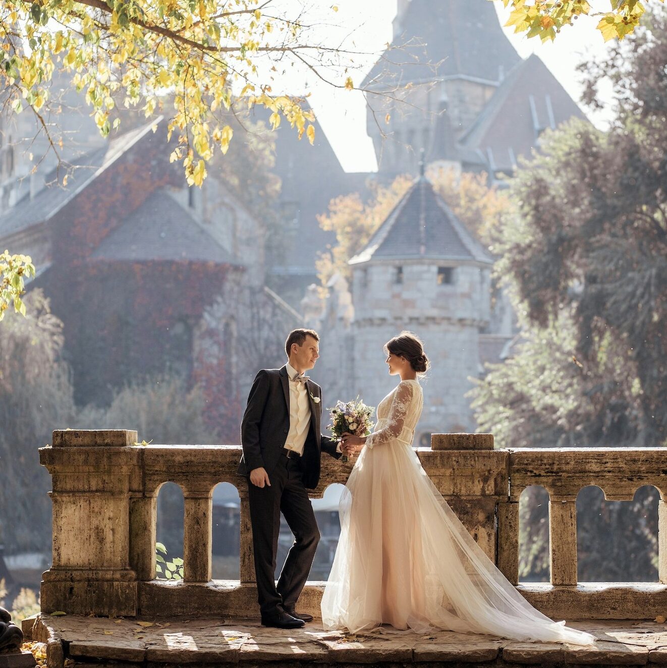 Wedding couple standing in front of stone wall in France.